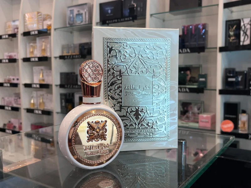 Perfume Árabe com embalagem e frasco com detalhes em rosé metalizado e fundo na cor branca. O perfume pode ser encontrado na loja Charlot, no Piso L2.