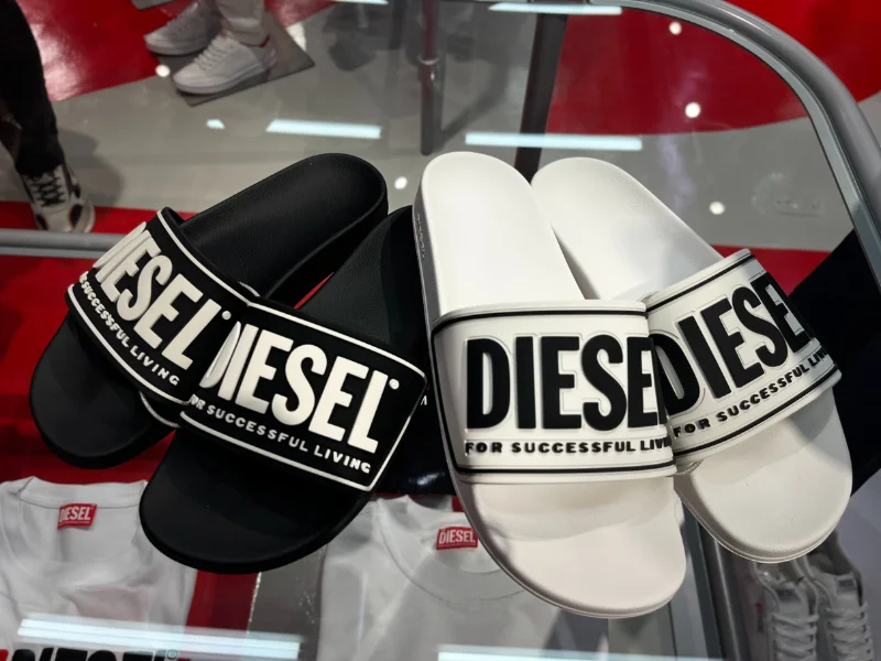 Sandálias nas cores preto e branco com a marca Diesel na parte superior.
