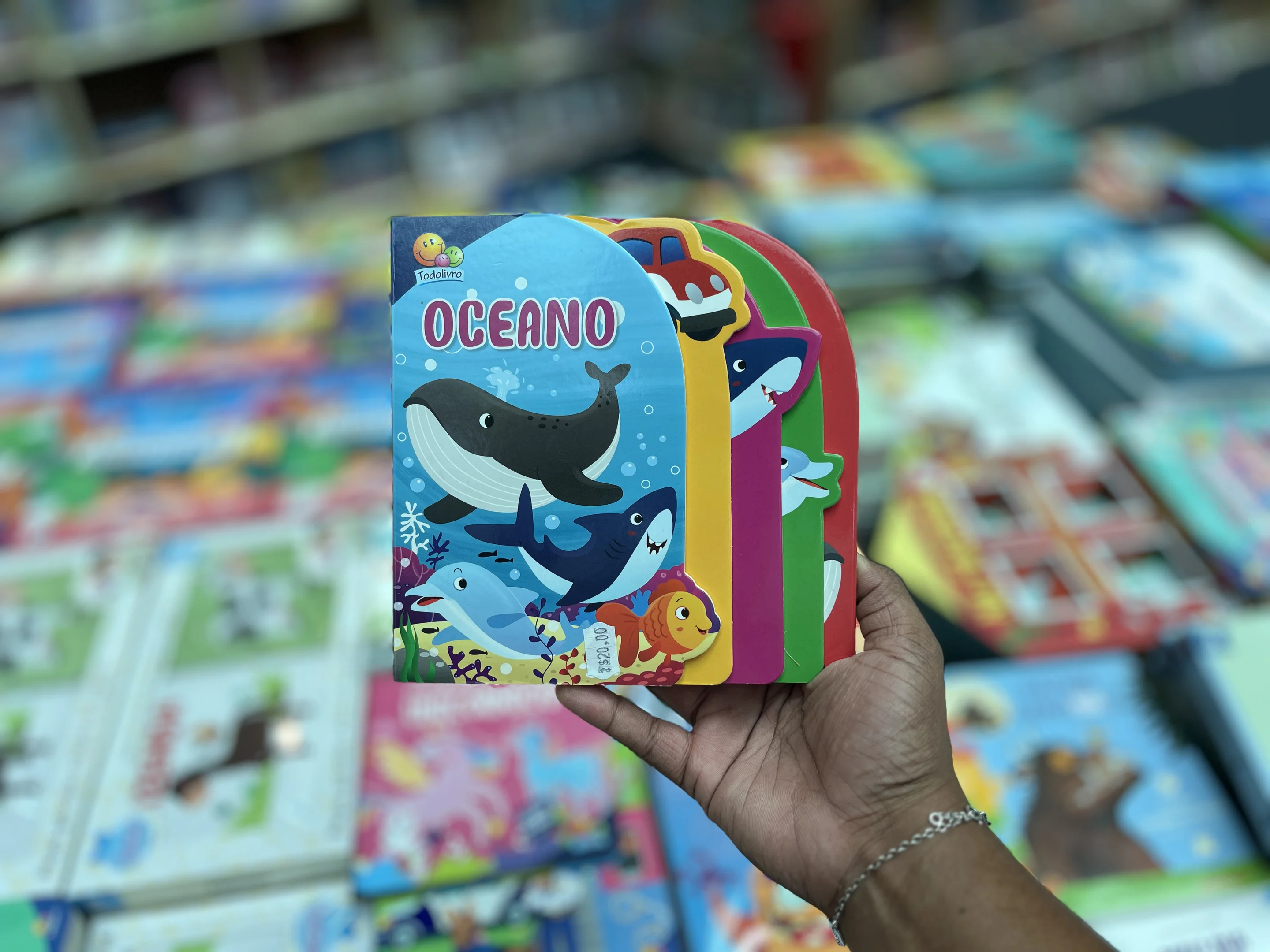 Mão masculina segurando o livro 'oceano', disponível na feira de livros BoraLê.